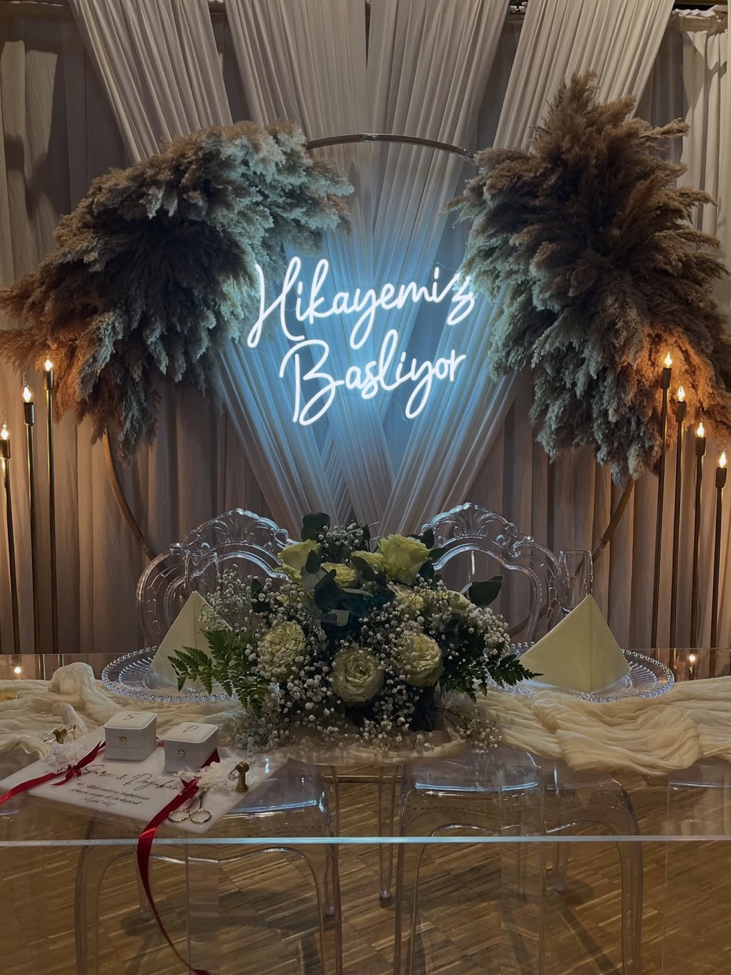 Verlobungstisch mit Pampas-Bogen, Neonschrift „Hikayemiz Başlıyor“ und weißen Rosen